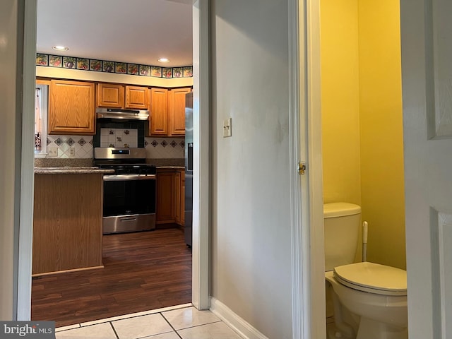 28 Willow Way Dr, Enola, PA 17025 - kitchen with stainless steel range, under cabinet range hood, tasteful backsplash, dark tile patterned flooring, and brown cabinets