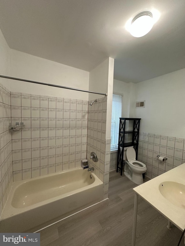 1009 W Susquehanna Ave, Philadelphia, PA 19122 - bathroom featuring wood finished floors, tile walls, shower / washtub combination, toilet, and a sink