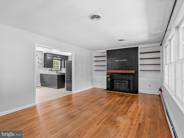 1002 Sherwood Cir, Salisbury, MD 21804 - unfurnished living room with a baseboard radiator, a brick fireplace, light wood-style flooring, and built in features