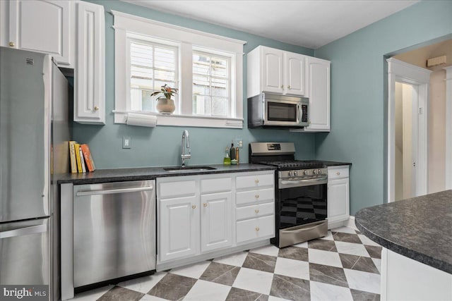 6721 Piney Branch Rd NW, Washington, DC 20012 - kitchen with appliances with stainless steel finishes, a sink, dark countertops, and white cabinetry