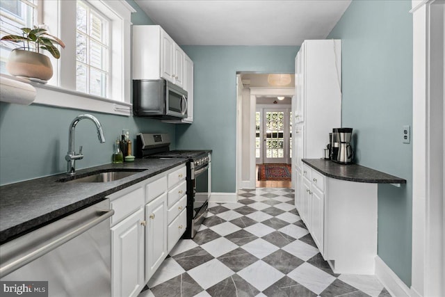 6721 Piney Branch Rd NW, Washington, DC 20012 - kitchen featuring stainless steel appliances, a sink, dark countertops, white cabinets, and baseboards