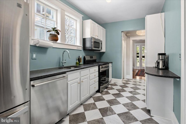 6721 Piney Branch Rd NW, Washington, DC 20012 - kitchen with stainless steel appliances, a sink, dark countertops, white cabinetry, and baseboards