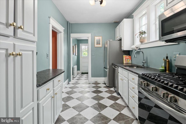 6721 Piney Branch Rd NW, Washington, DC 20012 - kitchen featuring stainless steel appliances, a sink, dark countertops, and white cabinets