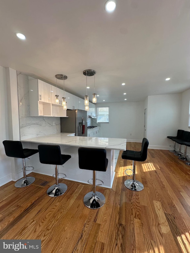 528 E Cheltenham Ave, Philadelphia, PA 19120 - kitchen with stainless steel fridge, modern cabinets, white cabinetry, a peninsula, and a breakfast bar area