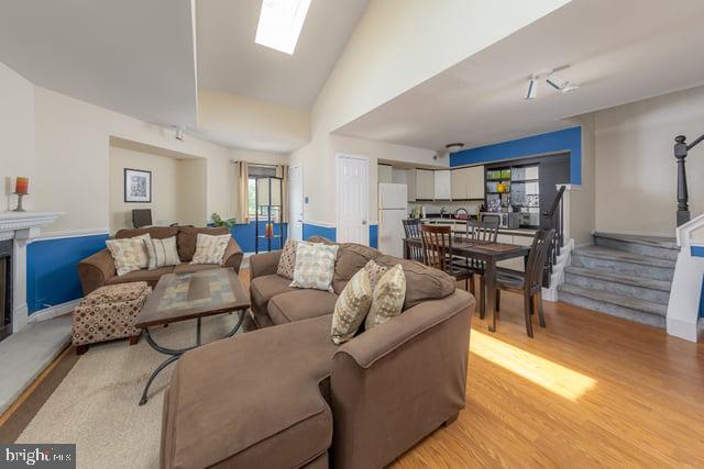 1004 Berwyck Ct, Sicklerville, NJ 08081 - living area featuring healthy amount of natural light, stairs, light wood finished floors, baseboards, and lofted ceiling