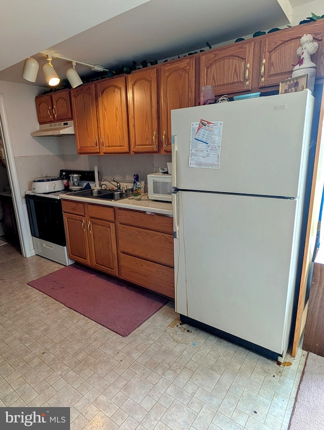 9933 Hoovers Hill Rd, Huntingdon, PA 16652 - kitchen with white appliances, under cabinet range hood, light countertops, brown cabinetry, and rail lighting