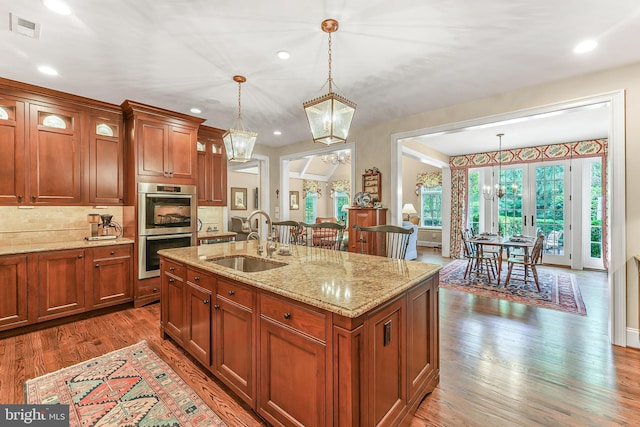 217 Valley Ridge Rd, Haverford, PA 19041 - kitchen featuring stainless steel double oven, a chandelier, hanging light fixtures, dark wood-type flooring, and light stone counters