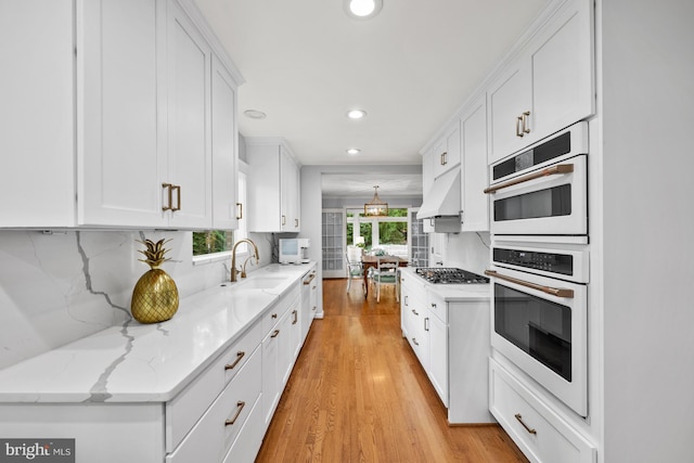 9017 Rouen Ln, Potomac, MD 20854 - kitchen with stainless steel gas stovetop, light wood-style floors, recessed lighting, white cabinetry, and a sink