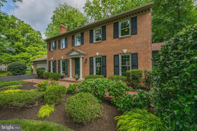 9017 Rouen Ln, Potomac, MD 20854 - colonial house with a chimney, brick siding, an attached garage, and driveway