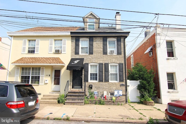 439 Prospect St, Bridgeport, PA 19405 - view of property featuring stone siding, cooling unit, stucco siding, and roof with shingles