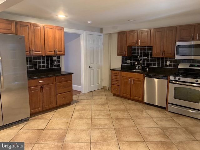 439 Prospect St, Bridgeport, PA 19405 - kitchen featuring appliances with stainless steel finishes, tasteful backsplash, dark countertops, light tile patterned floors, and brown cabinets