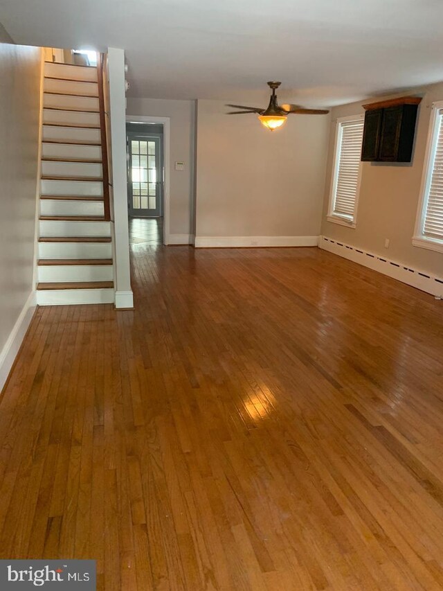 439 Prospect St, Bridgeport, PA 19405 - unfurnished living room with a baseboard radiator, hardwood / wood-style flooring, a ceiling fan, and stairway