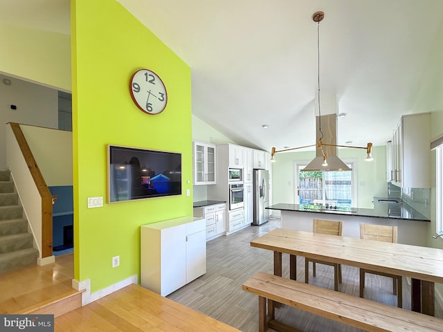 231 E Juniper Ave, Sterling, VA 20164 - kitchen with stainless steel appliances, dark countertops, white cabinets, light wood finished floors, and vaulted ceiling
