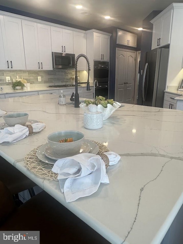 133 Henry Stoupe Way, Chester, MD 21619 - kitchen featuring stainless steel appliances, decorative backsplash, white cabinetry, and light stone counters
