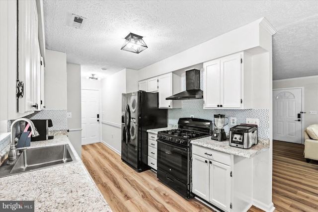 2569 N Independence Dr, Montross, VA 22520 - kitchen with black appliances, wall chimney exhaust hood, a textured ceiling, light wood finished floors, and white cabinetry