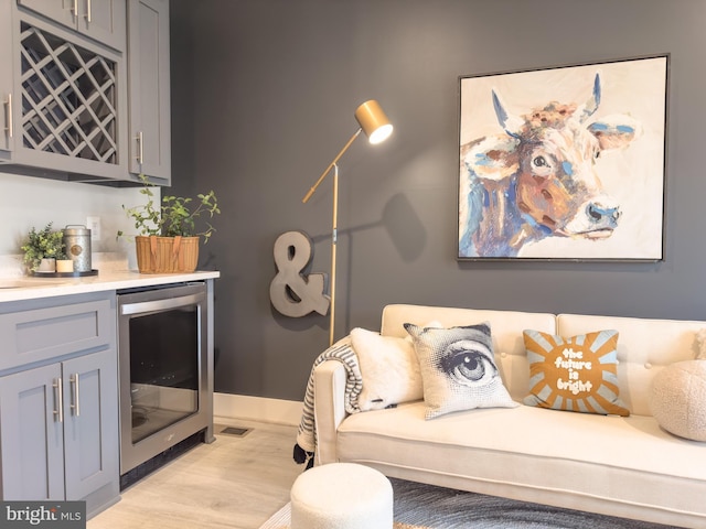 1949 Roland Clarke Pl, Reston, VA 20191 - sitting room featuring beverage cooler, a dry bar, light wood-style floors, and baseboards