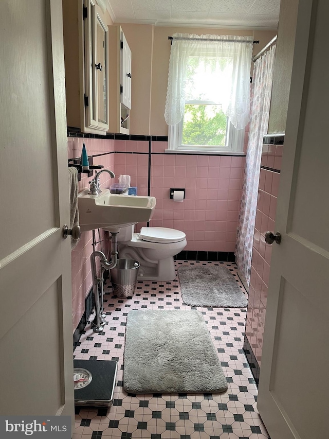 6936 Cedar Ave, Pennsauken, NJ 08109 - bathroom featuring a shower with shower curtain, tile walls, and wainscoting