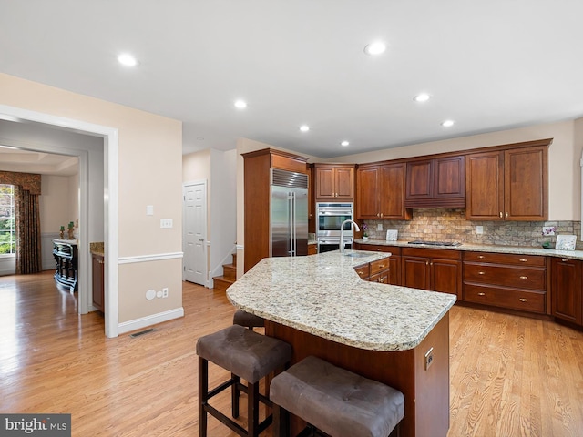 2 N Pheasants Rdg N, Wilmington, DE 19807 - kitchen with appliances with stainless steel finishes, light wood-style flooring, backsplash, an island with sink, and a kitchen breakfast bar