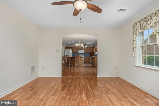 13336 Marquise Dr, Hagerstown, MD 21742 - unfurnished living room featuring a chandelier, light wood-type flooring, arched walkways, ceiling fan, and baseboards