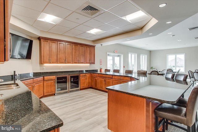13336 Marquise Dr, Hagerstown, MD 21742 - kitchen featuring wine cooler, a breakfast bar, brown cabinetry, a drop ceiling, and recessed lighting