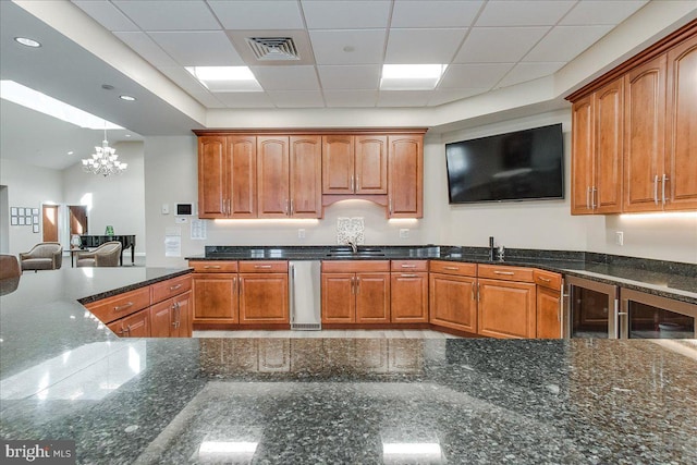 13336 Marquise Dr, Hagerstown, MD 21742 - kitchen with a chandelier, a sink, dark stone counters, brown cabinetry, and a drop ceiling