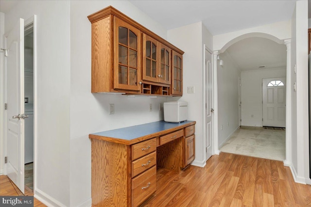 13336 Marquise Dr, Hagerstown, MD 21742 - kitchen featuring arched walkways, glass insert cabinets, ornate columns, and brown cabinets