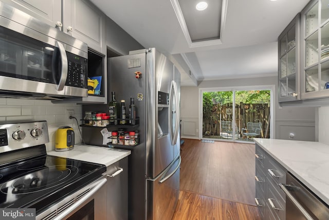 23 Penny Ln Unit 23, Baltimore, MD 21209 - kitchen featuring appliances with stainless steel finishes, dark wood finished floors, tasteful backsplash, light stone counters, and glass insert cabinets
