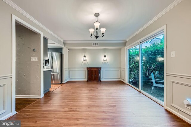 23 Penny Ln Unit 23, Baltimore, MD 21209 - unfurnished dining area featuring a chandelier, crown molding, wood finished floors, a wainscoted wall, and a decorative wall