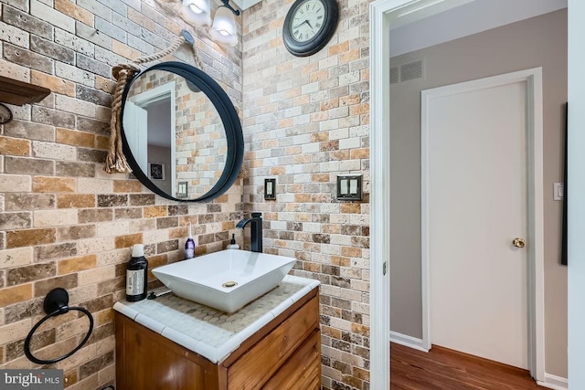 23 Penny Ln Unit 23, Baltimore, MD 21209 - bathroom featuring vanity, wood finished floors, and brick wall