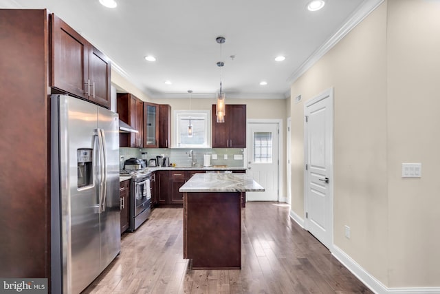 1128 S 24th St S, Philadelphia, PA 19146 - kitchen with stainless steel appliances, decorative light fixtures, backsplash, crown molding, and light wood finished floors
