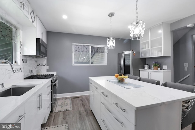 104 Ferndale Rd, Glen Burnie, MD 21061 - kitchen featuring stainless steel appliances, a chandelier, a kitchen island, a kitchen breakfast bar, and wood finished floors