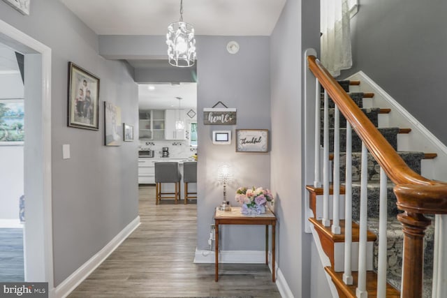 104 Ferndale Rd, Glen Burnie, MD 21061 - hallway featuring wood finished floors, stairs, and a chandelier