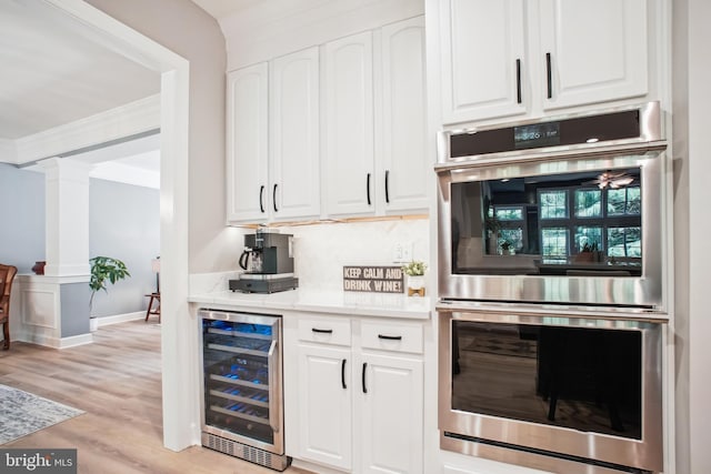 18510 Barton Creek Pl, Leesburg, VA 20176 - indoor bar with stainless steel double oven, beverage cooler, ornate columns, light wood-style floors, and crown molding