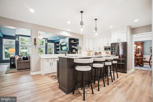 18510 Barton Creek Pl, Leesburg, VA 20176 - kitchen featuring appliances with stainless steel finishes, light countertops, a breakfast bar, light wood-type flooring, and white cabinetry
