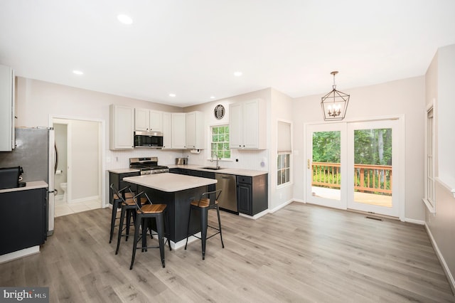 12424 Silent Wolf Dr, Manassas, VA 20112 - kitchen with stainless steel appliances, light countertops, a chandelier, light wood-style floors, and healthy amount of natural light