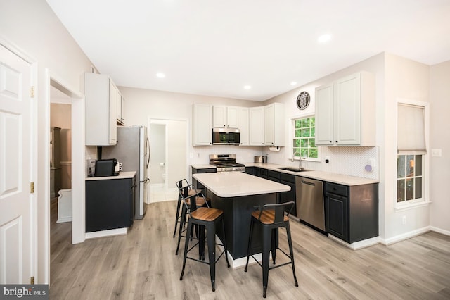 12424 Silent Wolf Dr, Manassas, VA 20112 - kitchen featuring stainless steel appliances, a breakfast bar, light wood finished floors, backsplash, and recessed lighting
