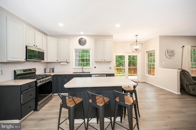 12424 Silent Wolf Dr, Manassas, VA 20112 - kitchen featuring appliances with stainless steel finishes, a breakfast bar area, light wood-type flooring, backsplash, and recessed lighting