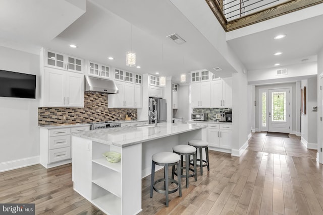1631 E Strasburg Rd, West Chester, PA 19380 - kitchen with under cabinet range hood, freestanding refrigerator, open shelves, a kitchen bar, and tasteful backsplash