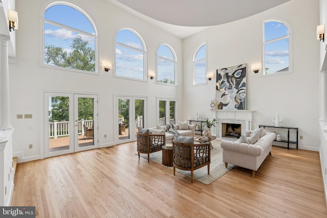 9309 Bells Mill Rd, Potomac, MD 20854 - living room with a high ceiling, decorative columns, a high end fireplace, light wood finished floors, and french doors
