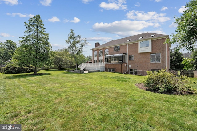 9309 Bells Mill Rd, Potomac, MD 20854 - rear view of house featuring a lawn, a chimney, brick siding, and a wooden deck