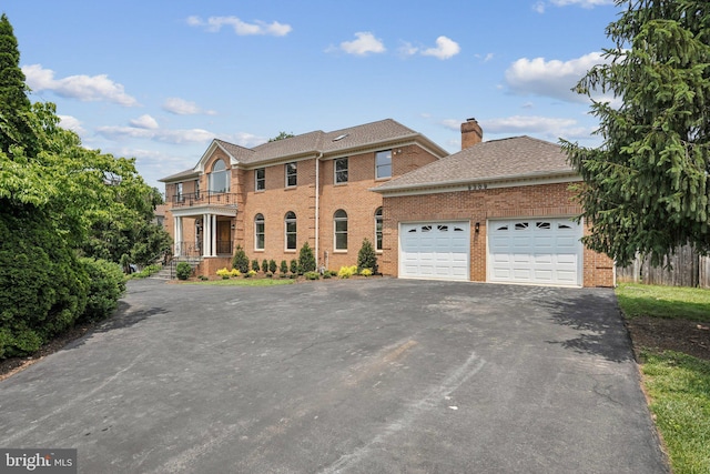 9309 Bells Mill Rd, Potomac, MD 20854 - colonial home with a balcony, asphalt driveway, brick siding, an attached garage, and a chimney