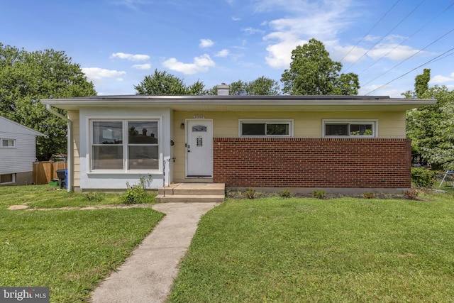 2306 Louise Ave, Baltimore, MD 21214 - view of front facade with a front yard, a chimney, brick siding, and roof mounted solar panels