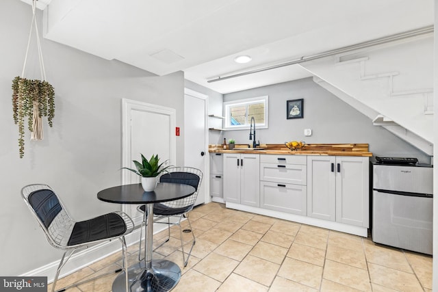 3010 26th St NE, Washington, DC 20018 - kitchen featuring wood counters, white cabinetry, refrigerator, and light tile patterned flooring