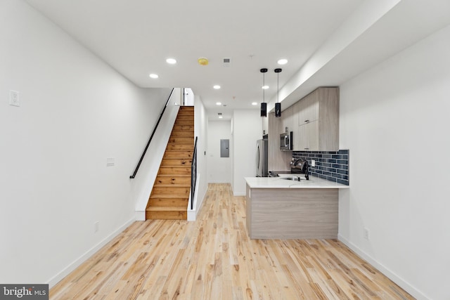 5937 Osage Ave Unit B, Philadelphia, PA 19143 - kitchen with appliances with stainless steel finishes, tasteful backsplash, a peninsula, light countertops, and light wood-style floors