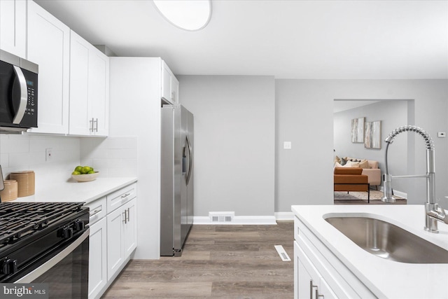 8119 Clyde Bank Rd, Towson, MD 21286 - kitchen with stainless steel appliances, light wood-type flooring, light countertops, decorative backsplash, and white cabinetry