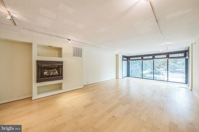 1520 16th St NW Unit 101, Washington, DC 20036 - unfurnished living room featuring rail lighting, floor to ceiling windows, wood finished floors, and a fireplace