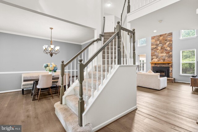 818 Northridge Way, Severna Park, MD 21146 - stairs with wood finished floors, a fireplace, a chandelier, a towering ceiling, and crown molding