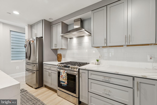 2108 4th St NE Unit A, Washington, DC 20002 - kitchen with wall chimney exhaust hood, appliances with stainless steel finishes, gray cabinetry, light wood-style flooring, and tasteful backsplash
