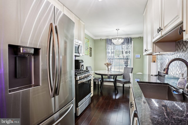 2203 Pyle St, Wilmington, DE 19805 - kitchen featuring stainless steel appliances, a chandelier, ornamental molding, dark wood-style floors, and dark stone counters