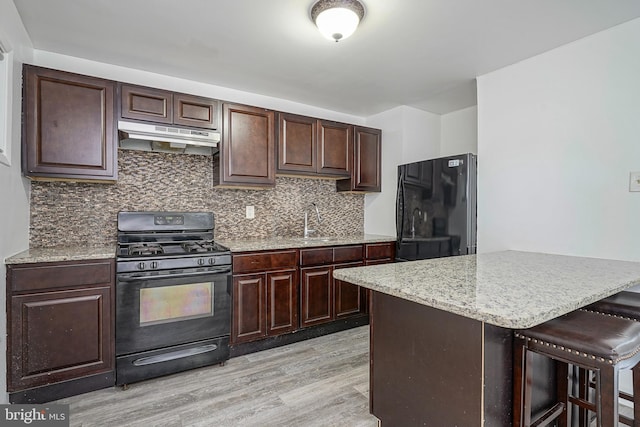 1549 S 8th St, Camden, NJ 08104 - kitchen with black range with gas cooktop, freestanding refrigerator, under cabinet range hood, light wood-style floors, and a sink